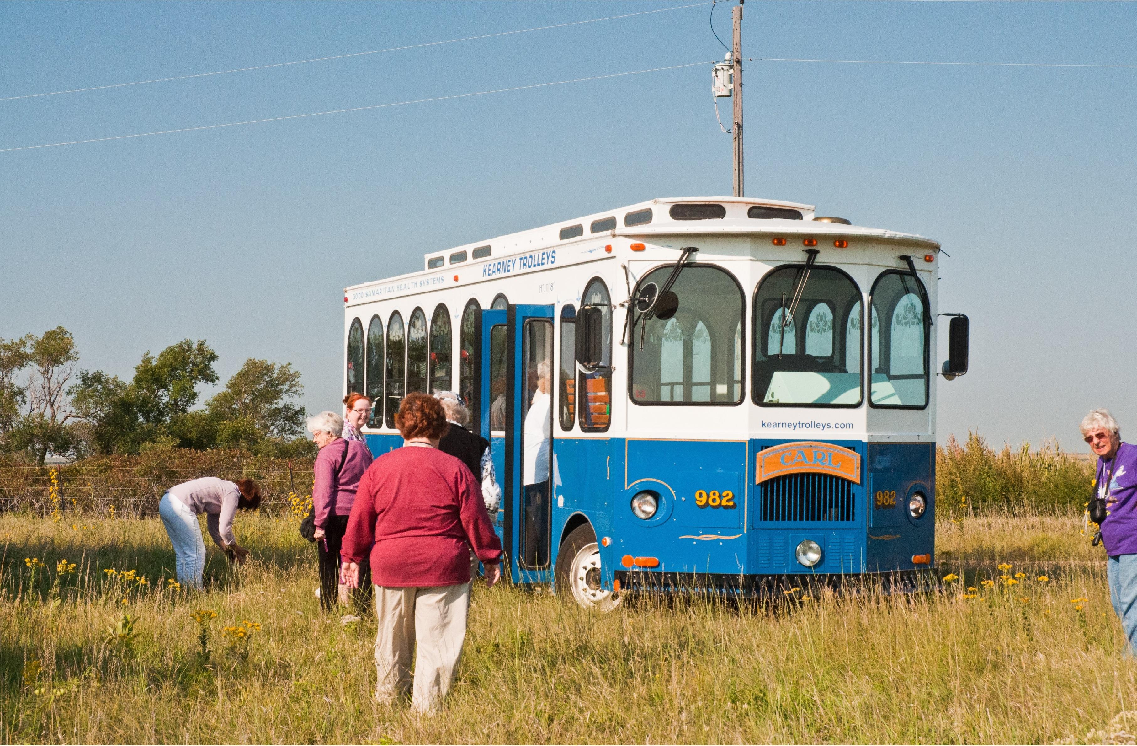 Visitors walk outside near a trolley bus.