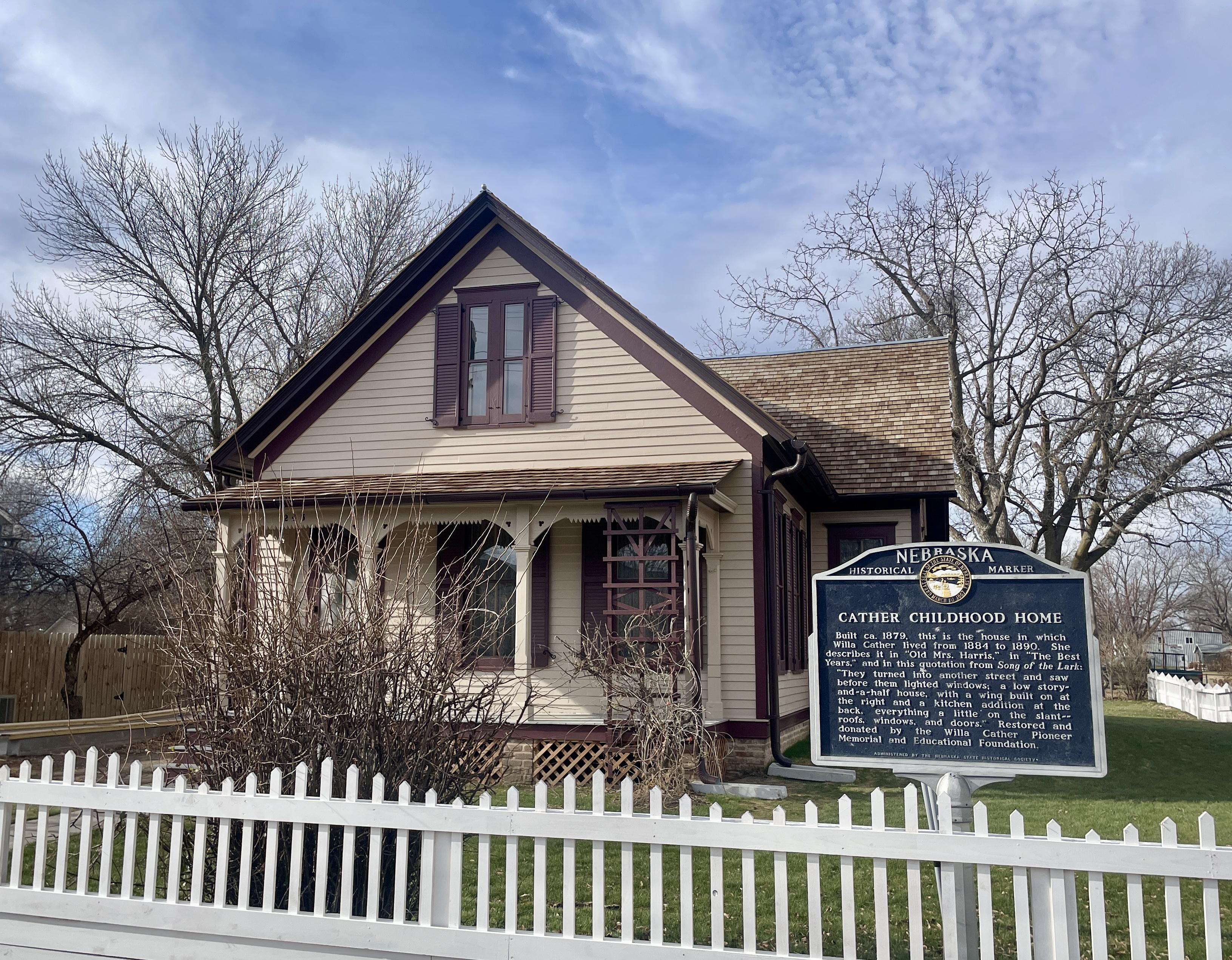 Exterior of Childhood Home with white picket fence and historic marker. 