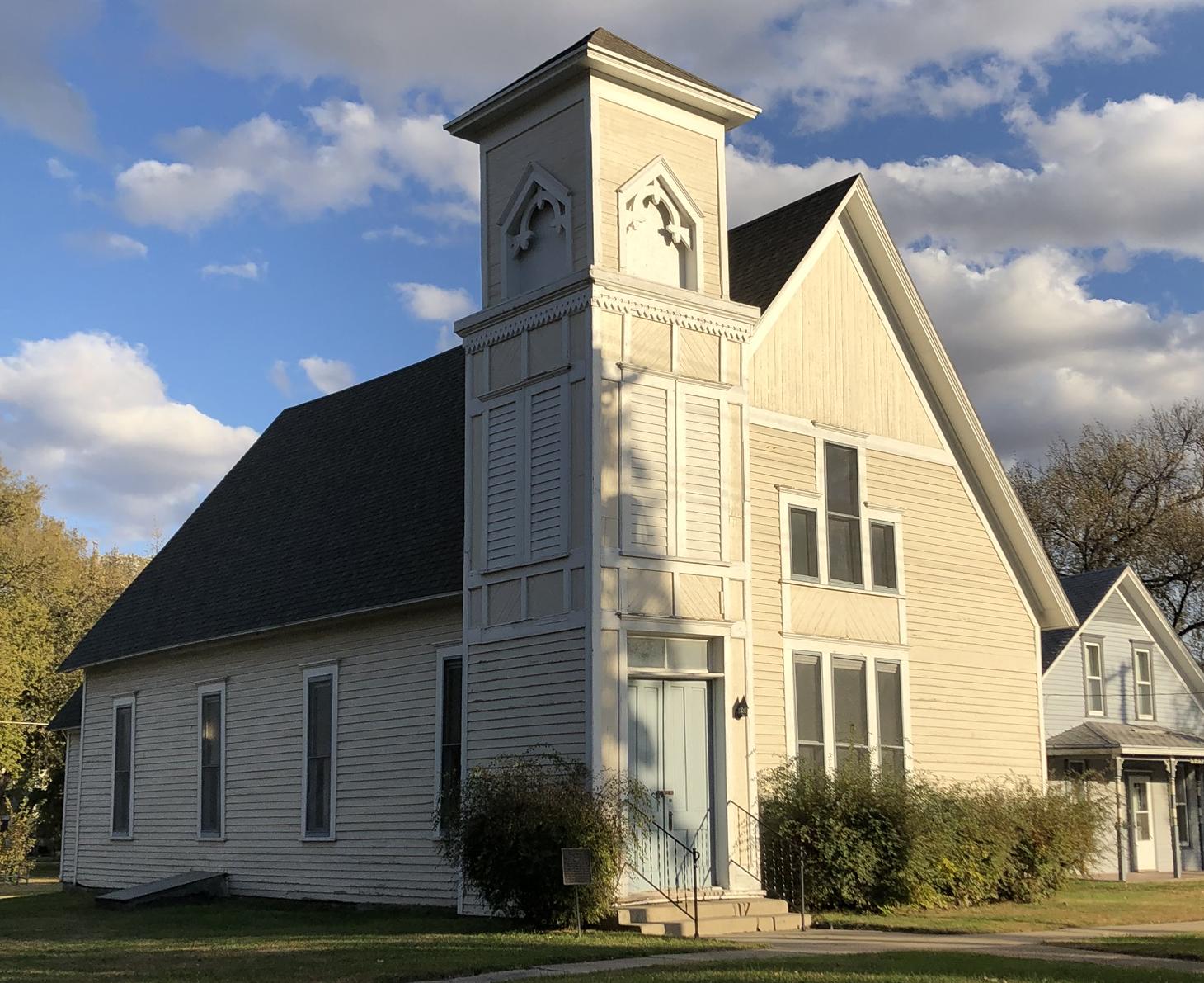 White church on a corner with blue sky and clouds