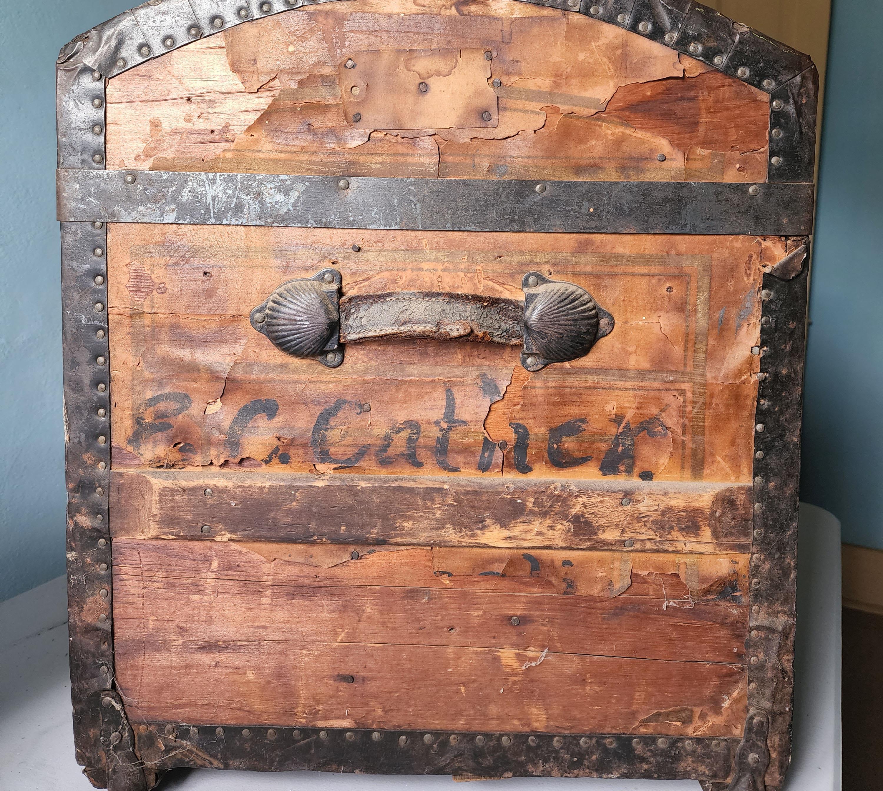 The brown E.C. Cather trunk (left side) with the name printed below the handle.