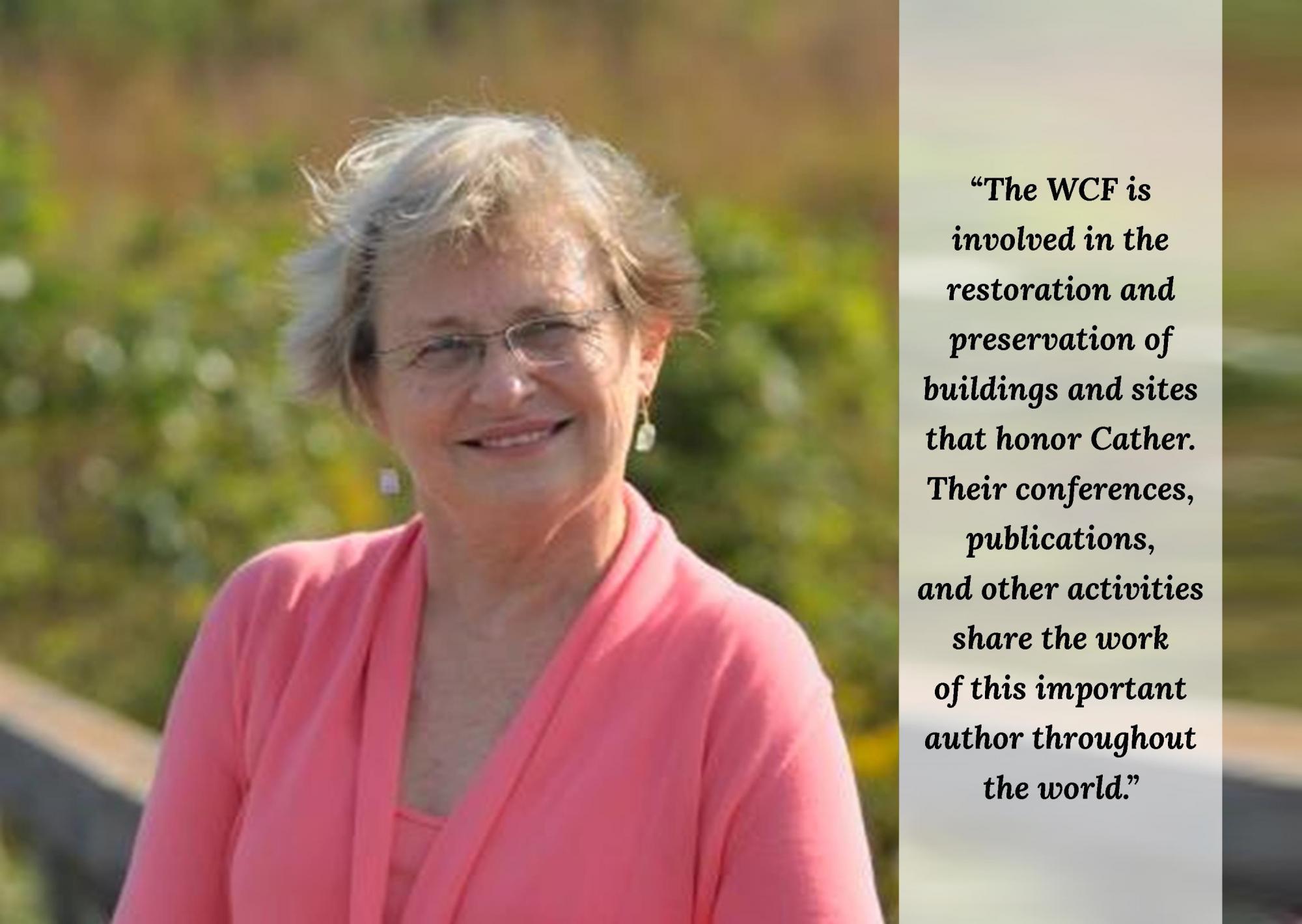 Jane Renner Hood stands with a garden behind her, wearing a pink shirt