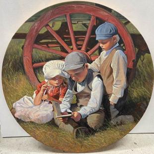 Three children in historic costumes read in front of wagon wheel