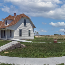 Fully restored Pavelka Farmstead with the root cellar in the foreground, accessible walkways, and interpretive signs.