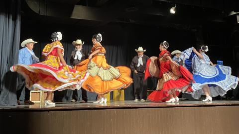 four women of Ballet Folkorico de Topeka in tradition dress dance on the Red Cloud Opera House stage