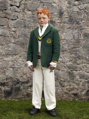 Boy with red hair photographed standing in front of rock wall