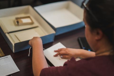 Woman looks at artifacts in archival box
