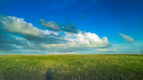 Spring prairie grassland with blue sky and dramatic clouds